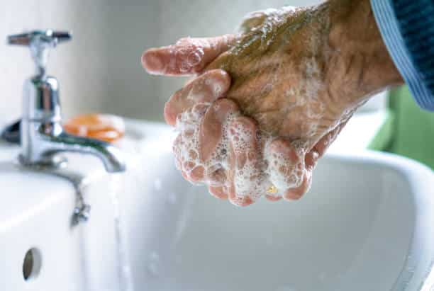 persona de la tercera edad lavándose las manos para protegerse del coronavirus